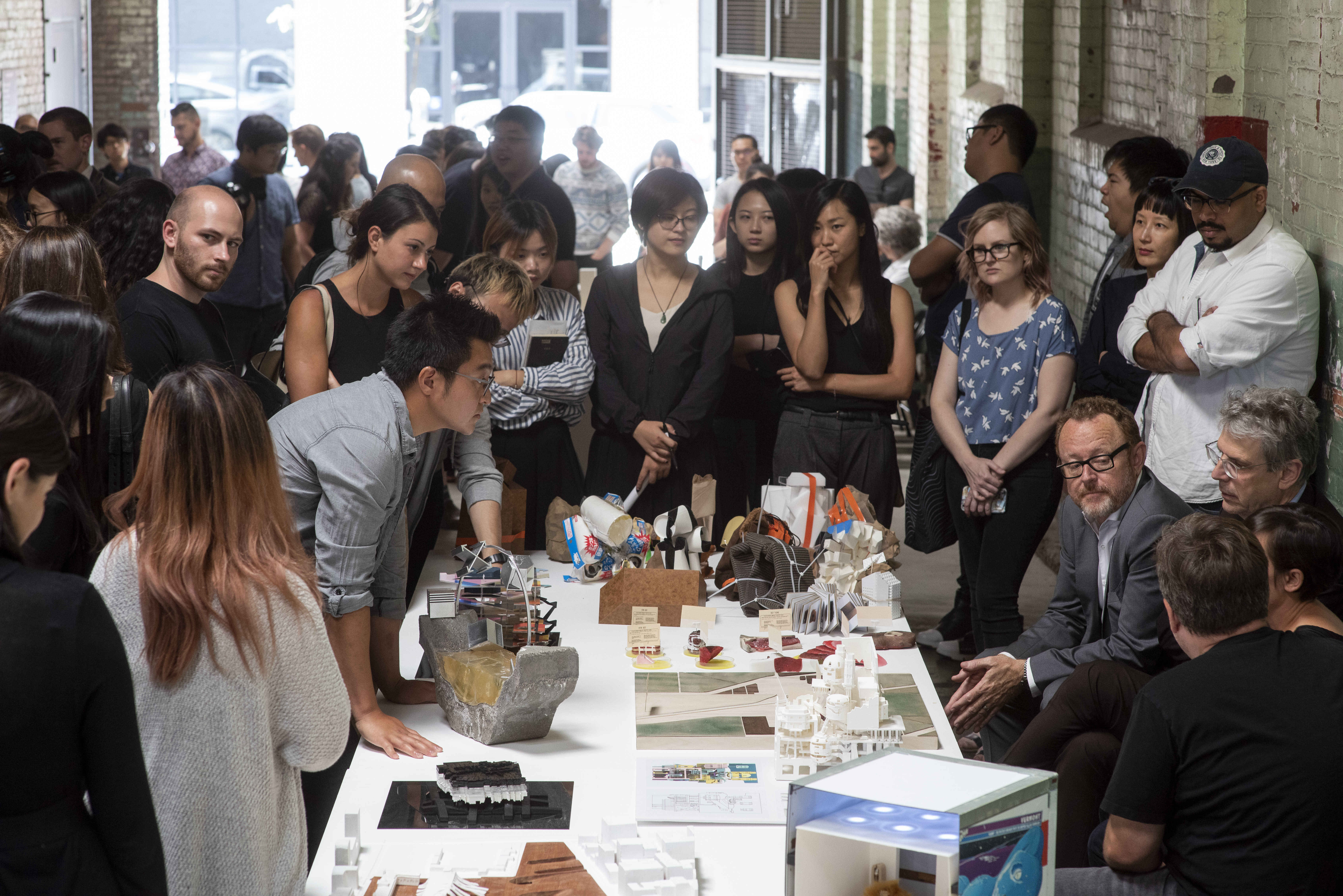 students presenting miniature thesis model brick corridor gallery