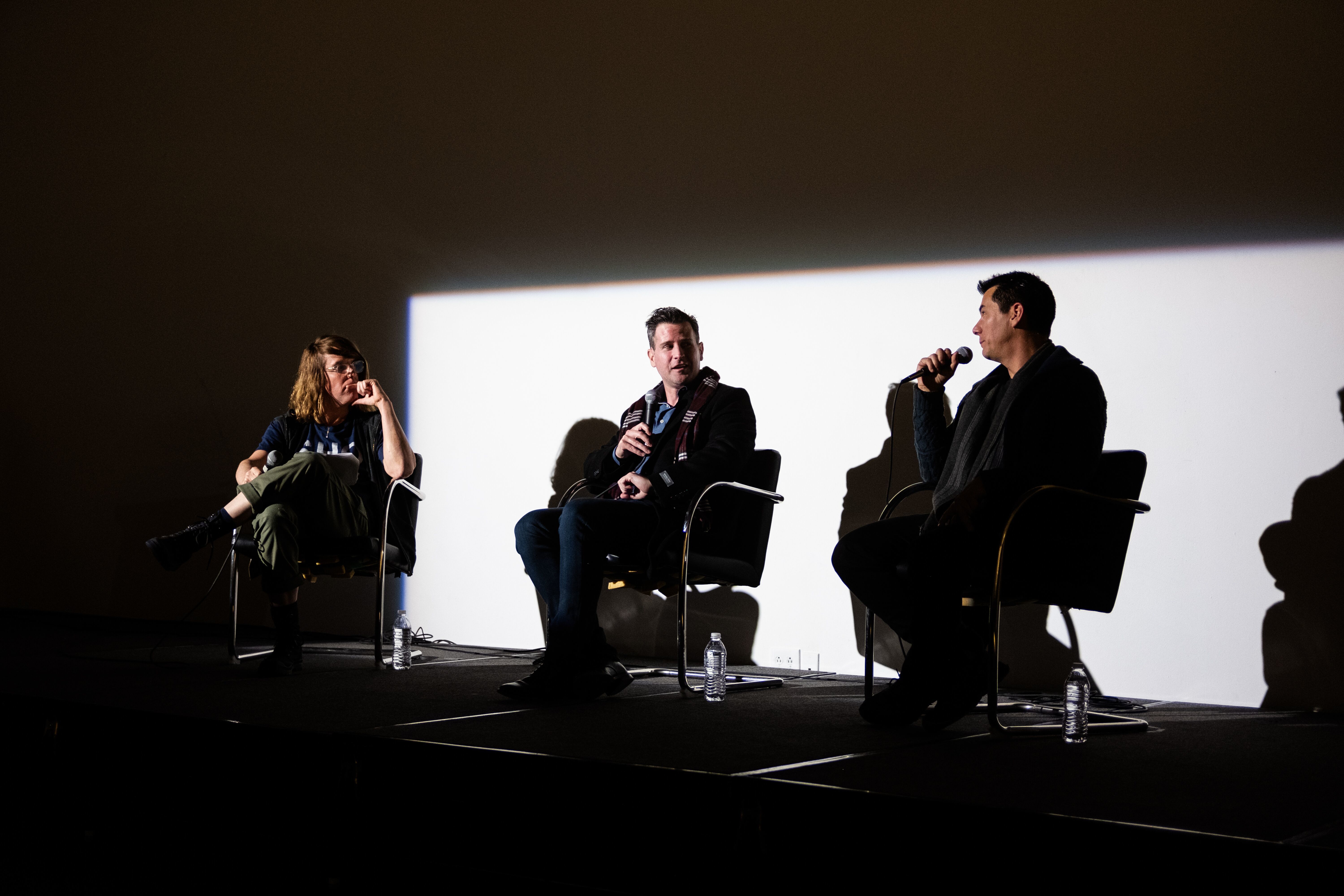 three men sitting on stage