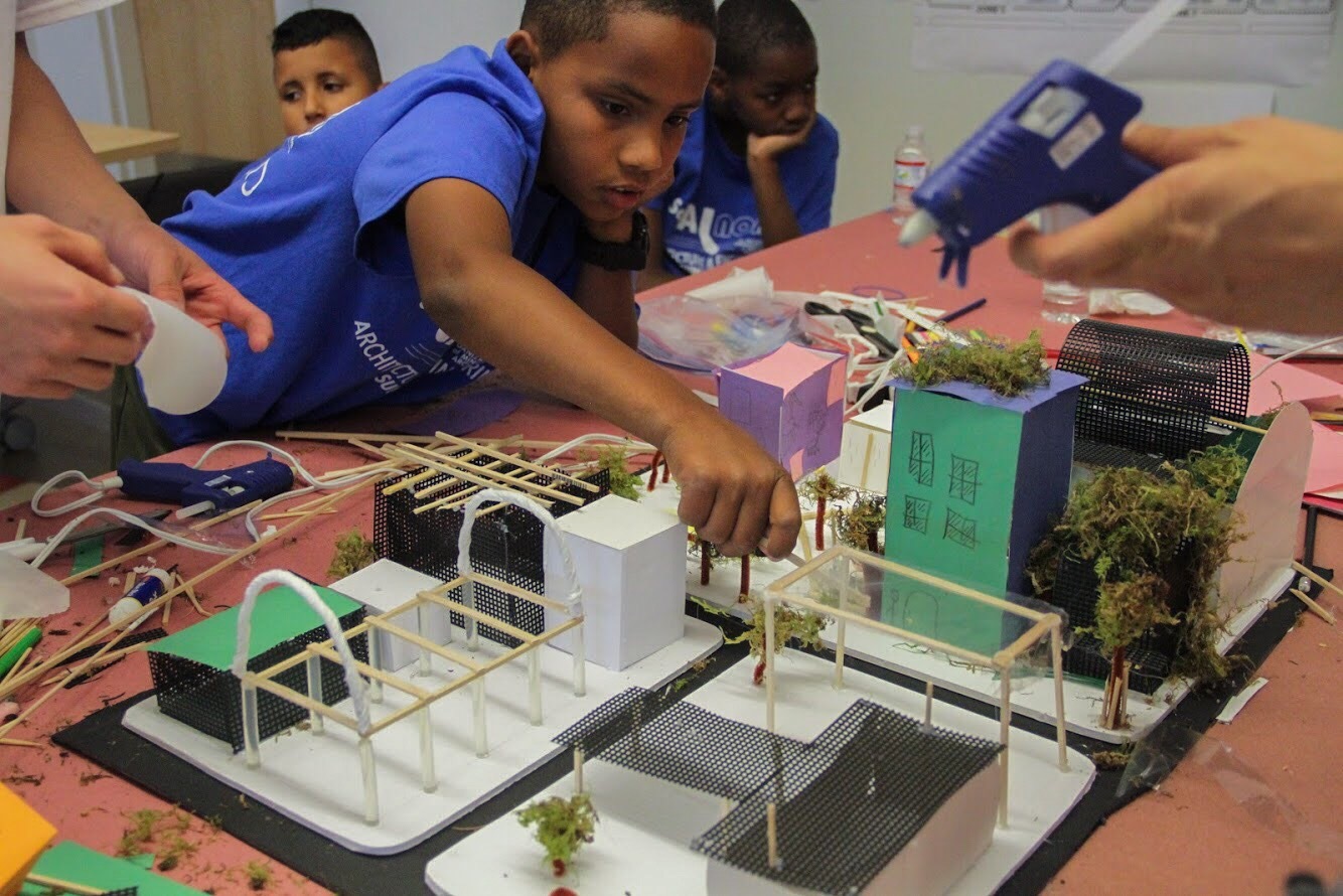 A school kid fabricating an architectural model made with bamboo sticks