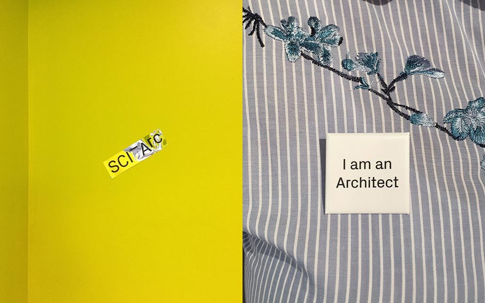 SCI-Arc silver sticker on yellow background and a SCI-Arc pin wore on a puple dress