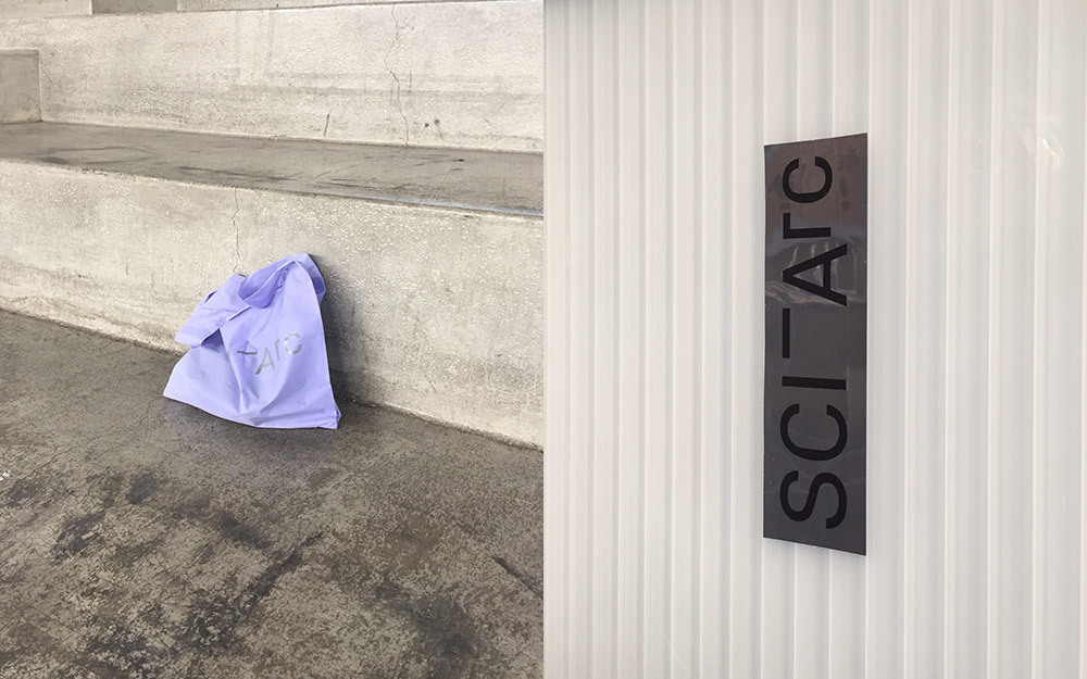 Purple SCI-Arc bag on cocrete stairs and a SCI-Arc silver sticker