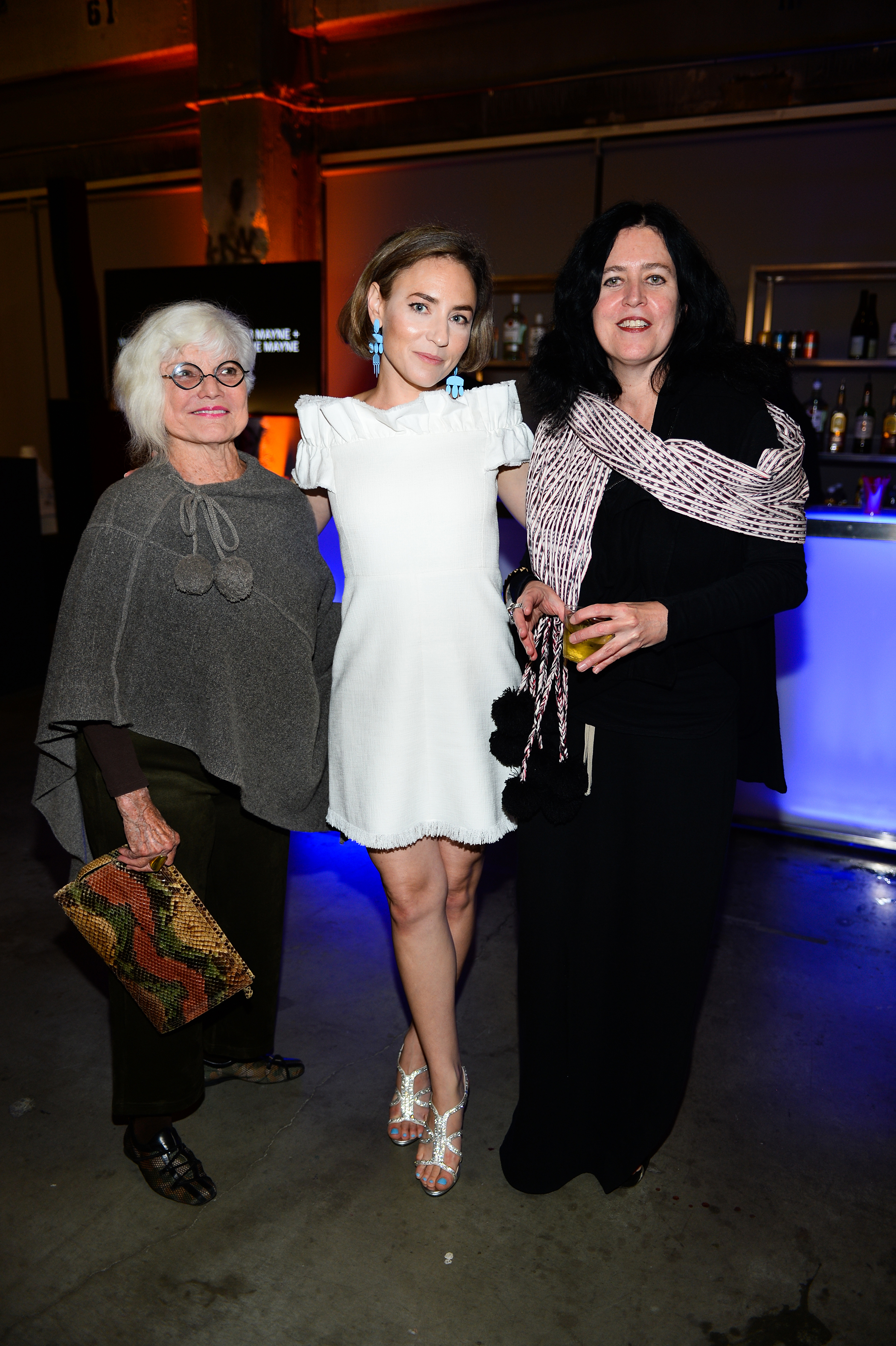 Three women stand and pose for a photo together.