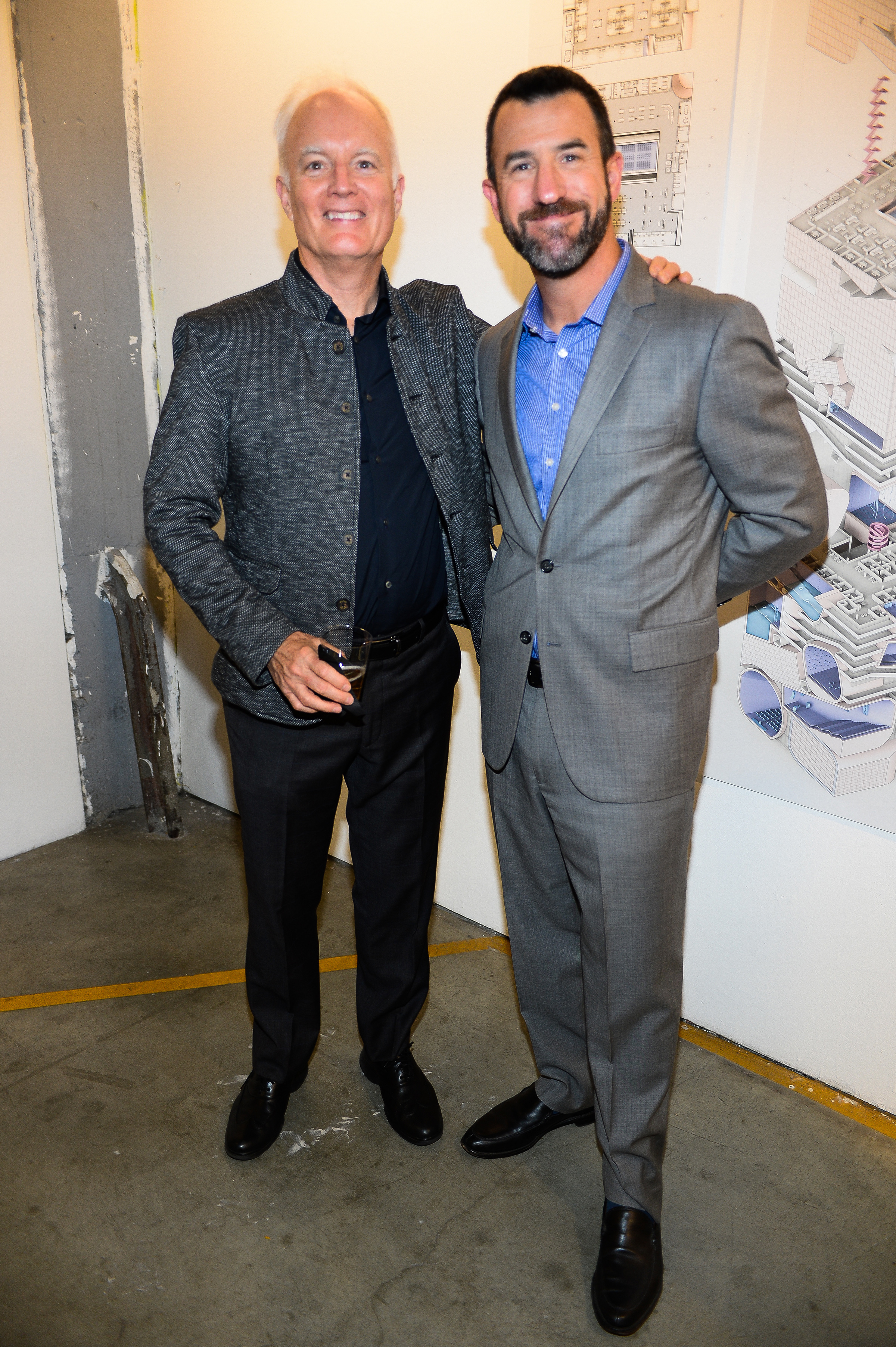 Two men in suits stand and pose together for a photo.