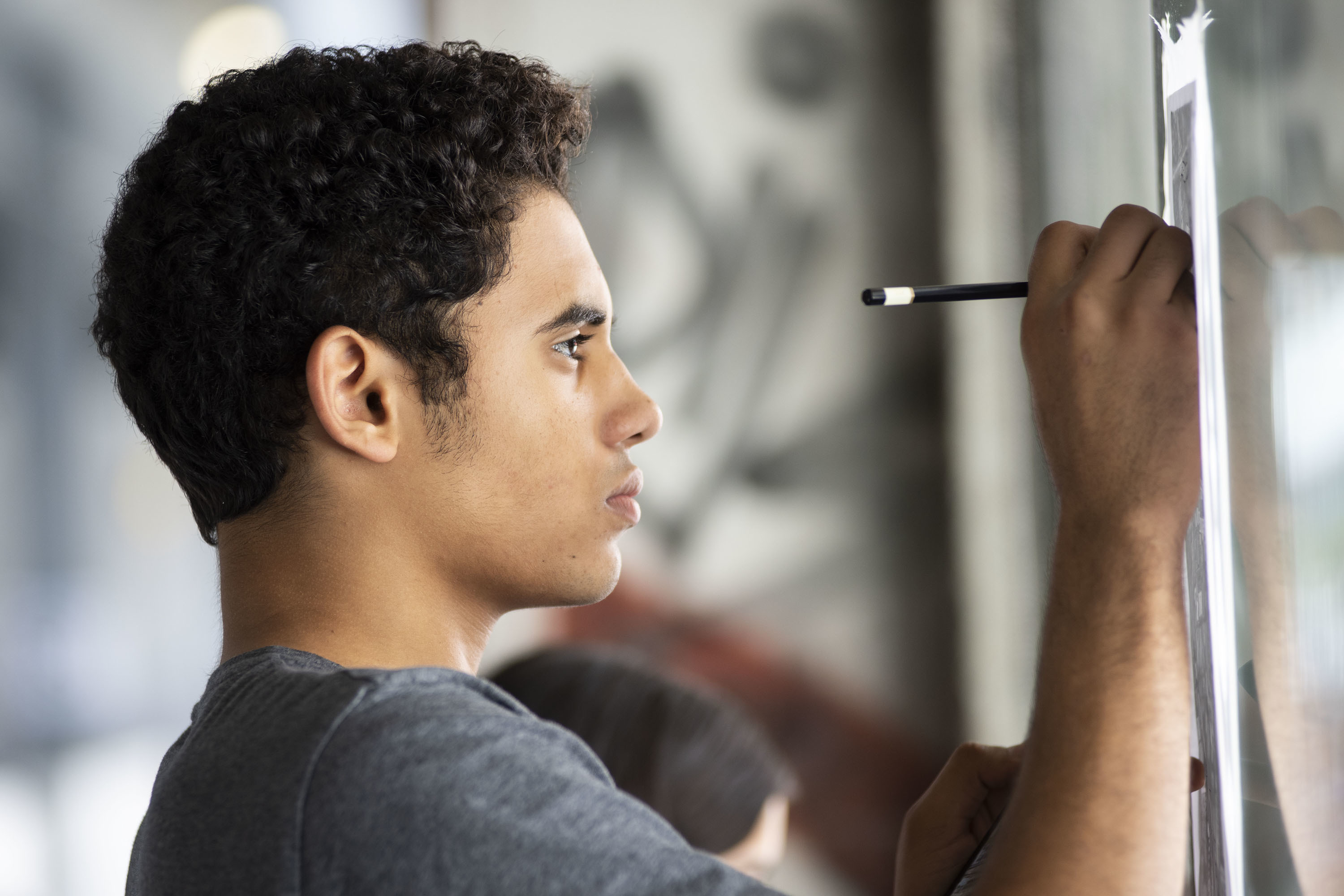 A boy drawing on paper supported on the wall