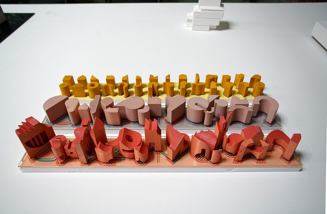 three architectural model of yellow pink and red colors respectively