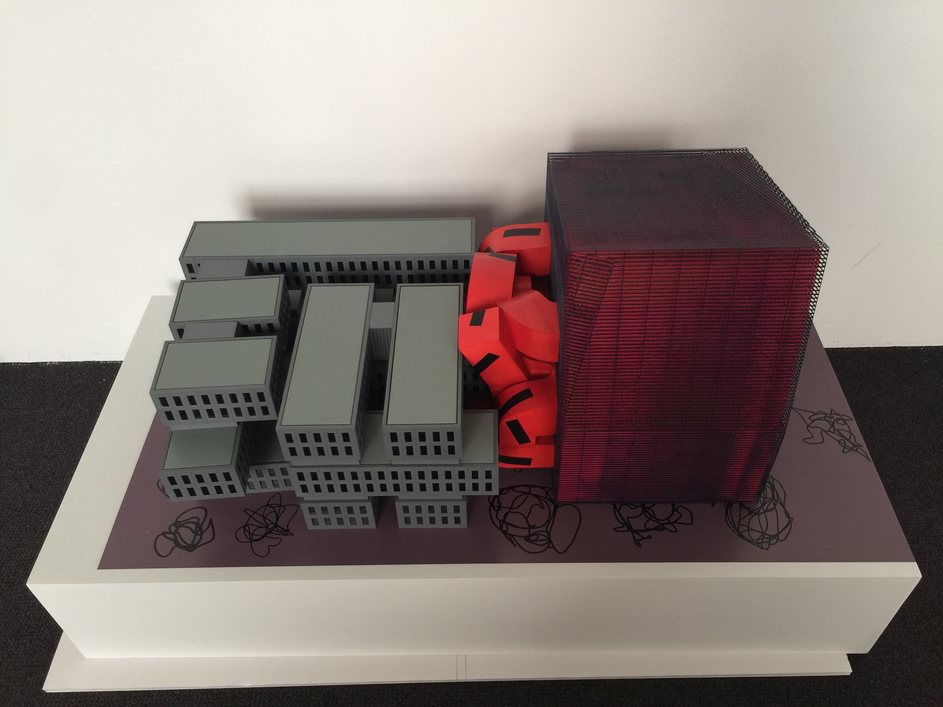 A red colored architectural model in a grey cage