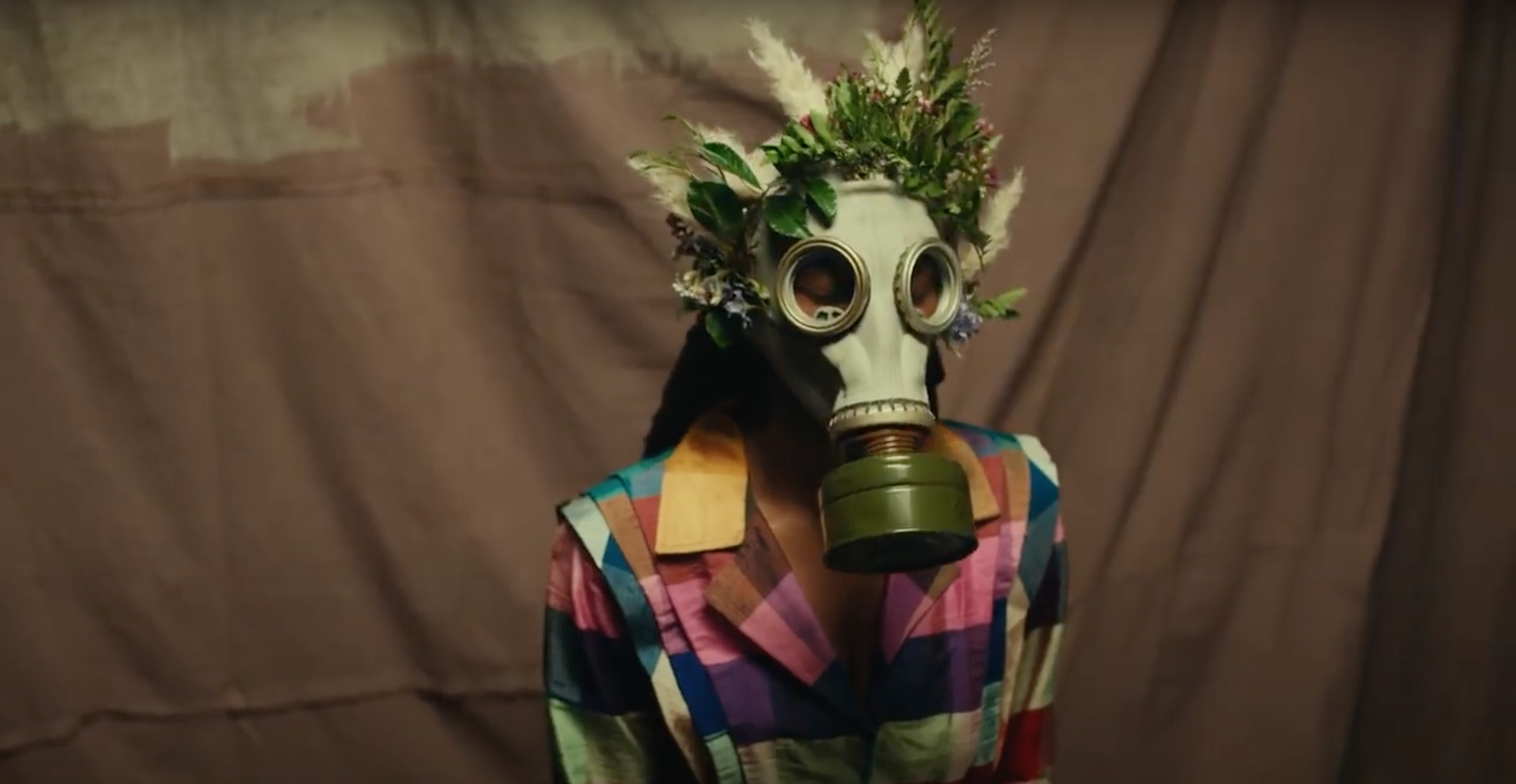 person wearing gas mask decorated in feathers