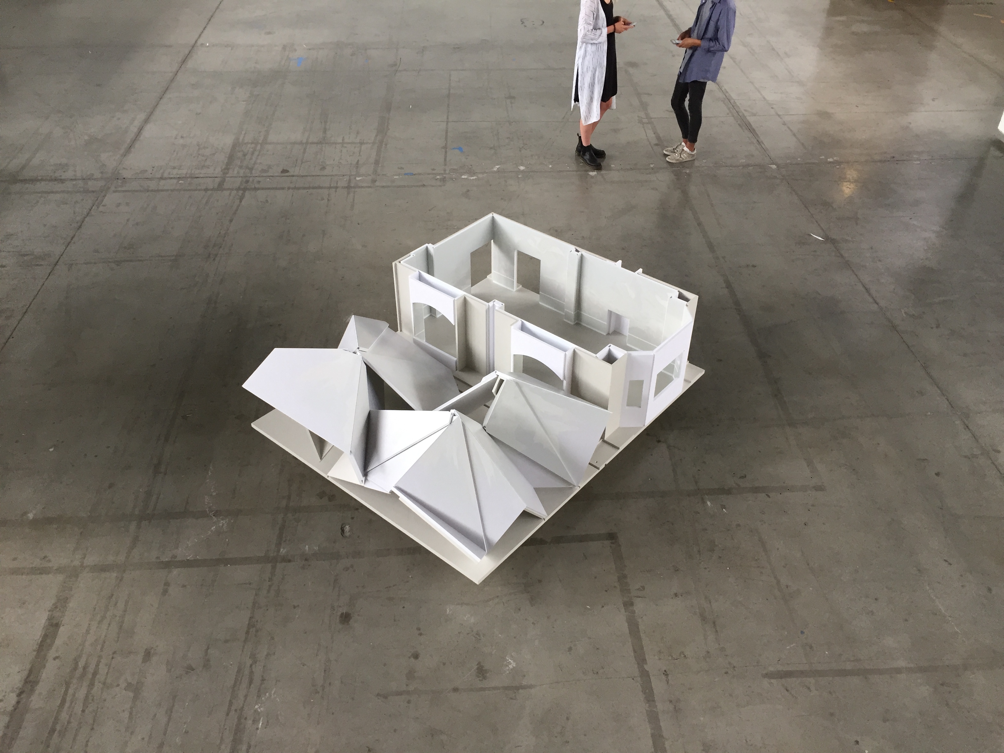 a huge architectural model with three disconstucted pyramids on a concrete floor