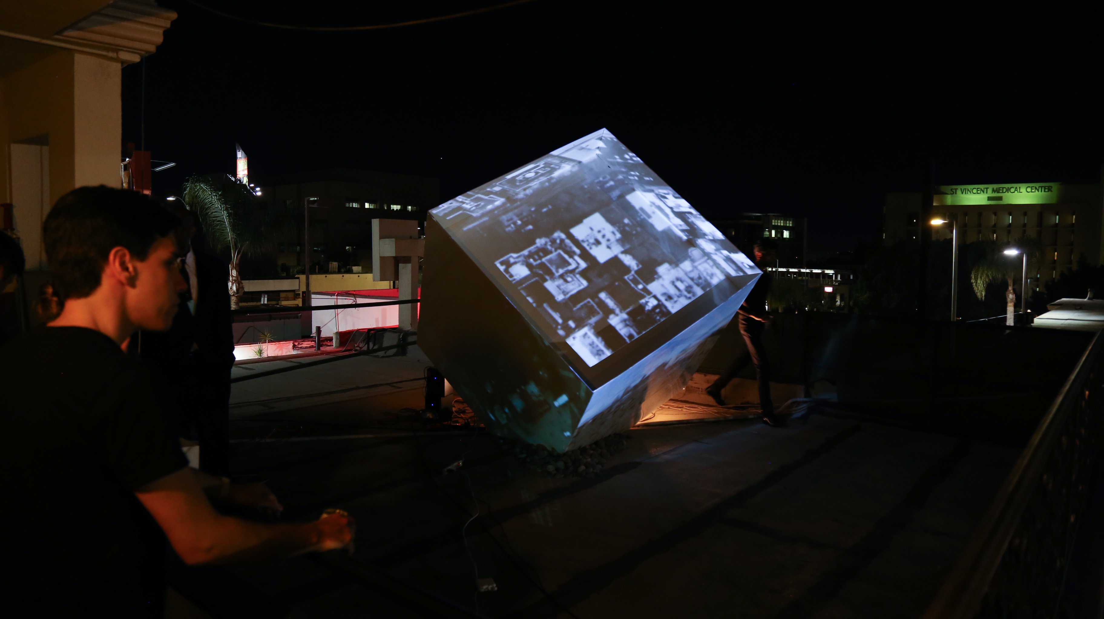 Art enthusiast admiring ahuge cube with projections on it at night