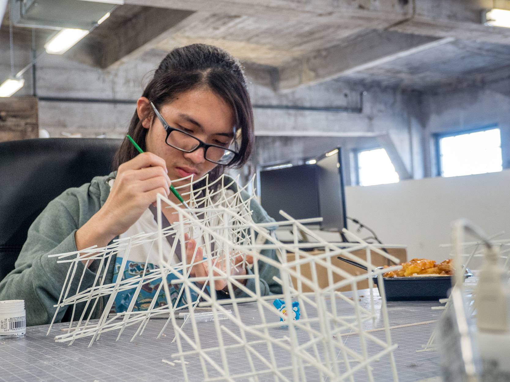 student paints plastic model at desk