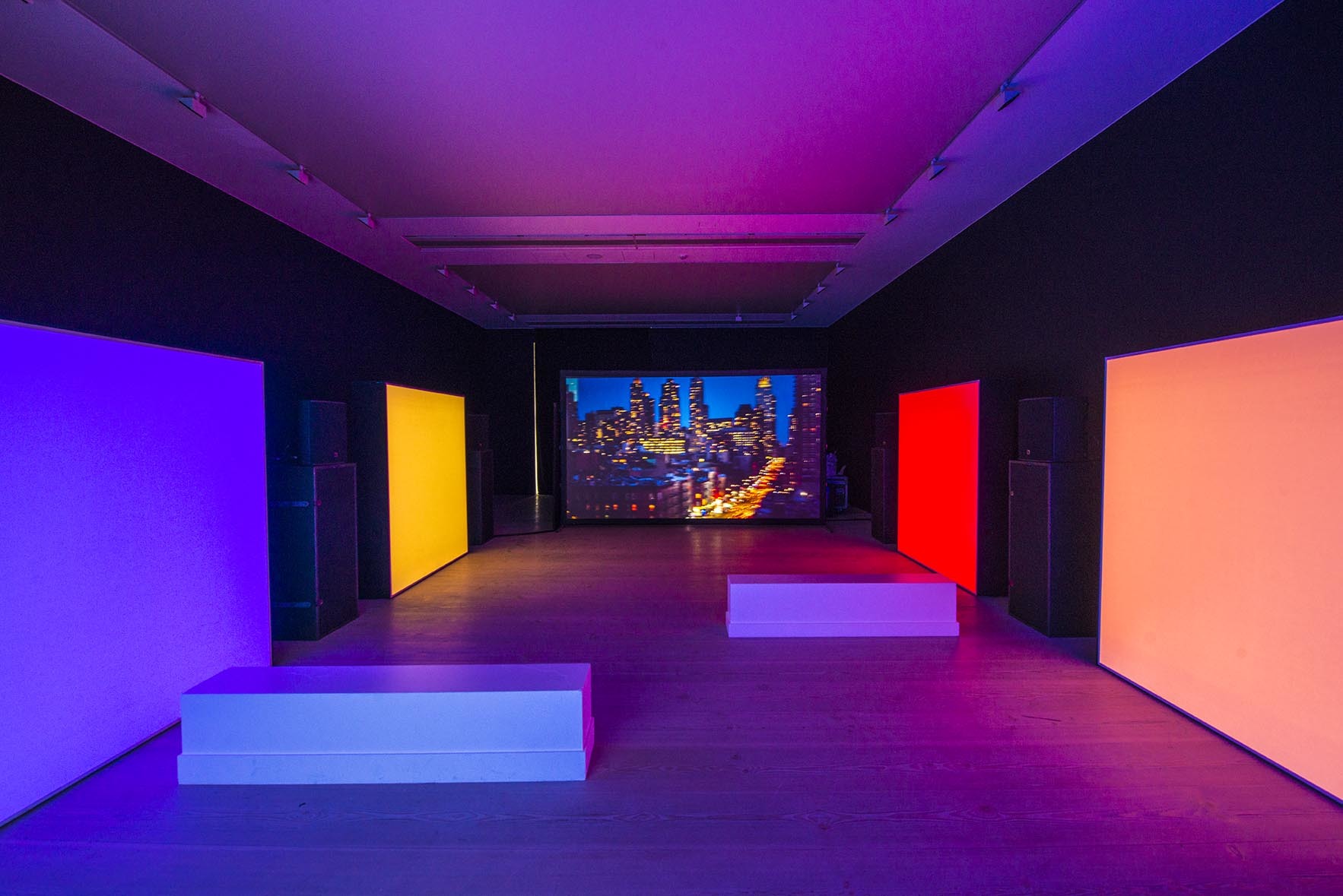 lit up prime colored boxes within dimly lit gallery