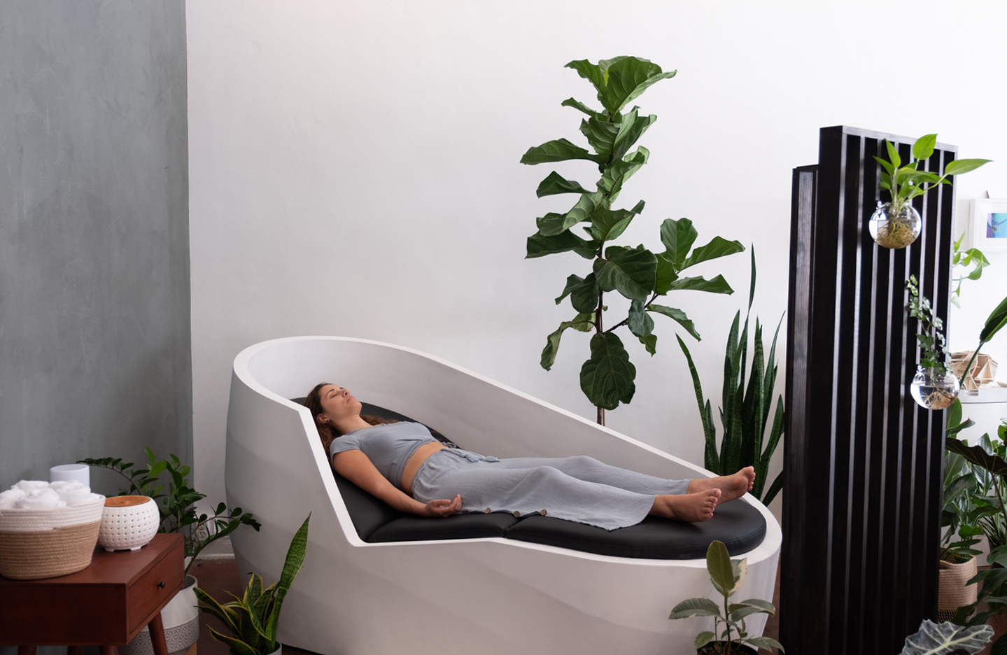 person lounging relaxing sleeping in Tech-embedded lounge chair for relaxation, by Neumascape Studio surrounded by green plants