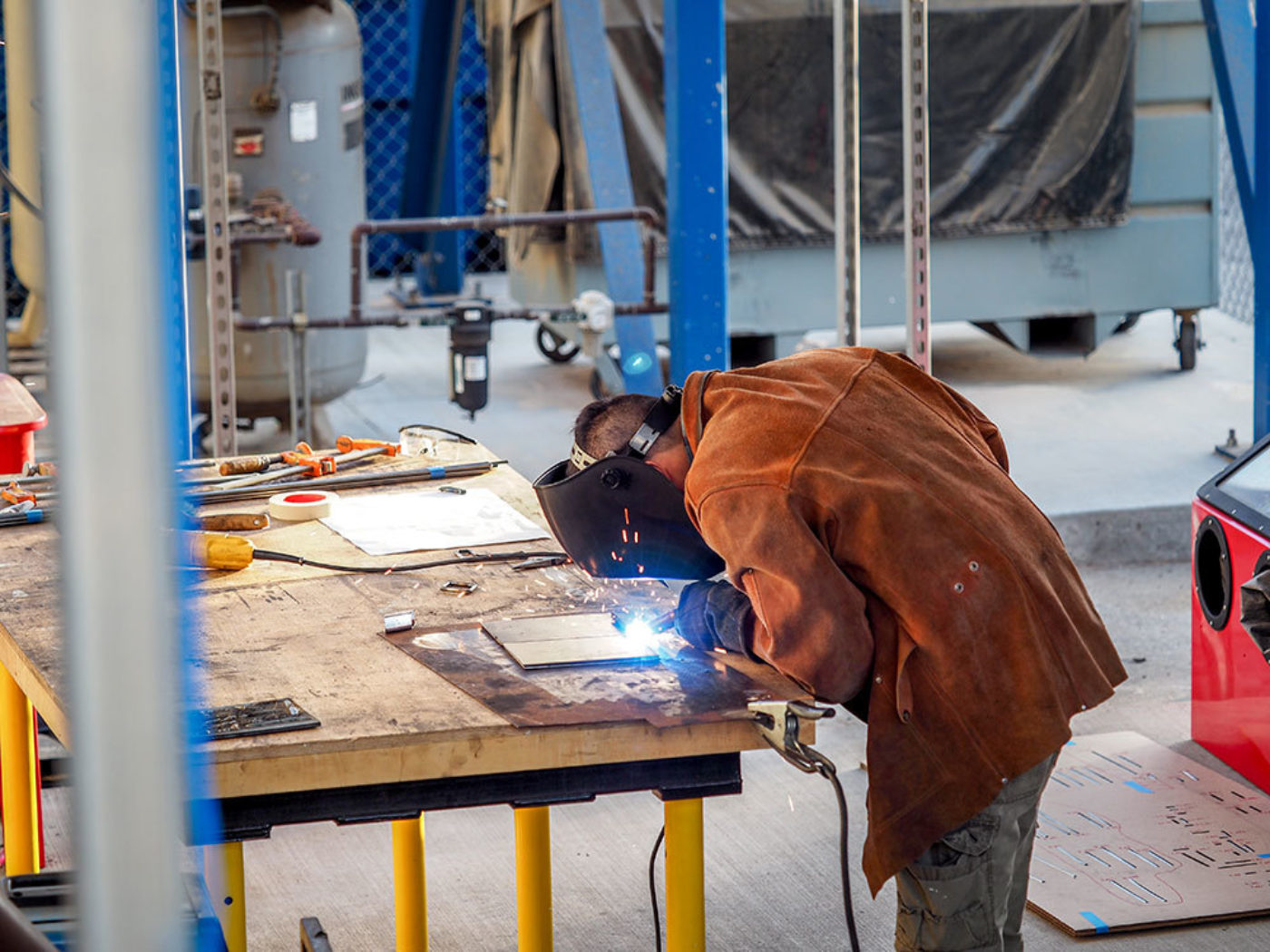 student in orange shirt welding steel architecture model in sci-arc shop architecture school