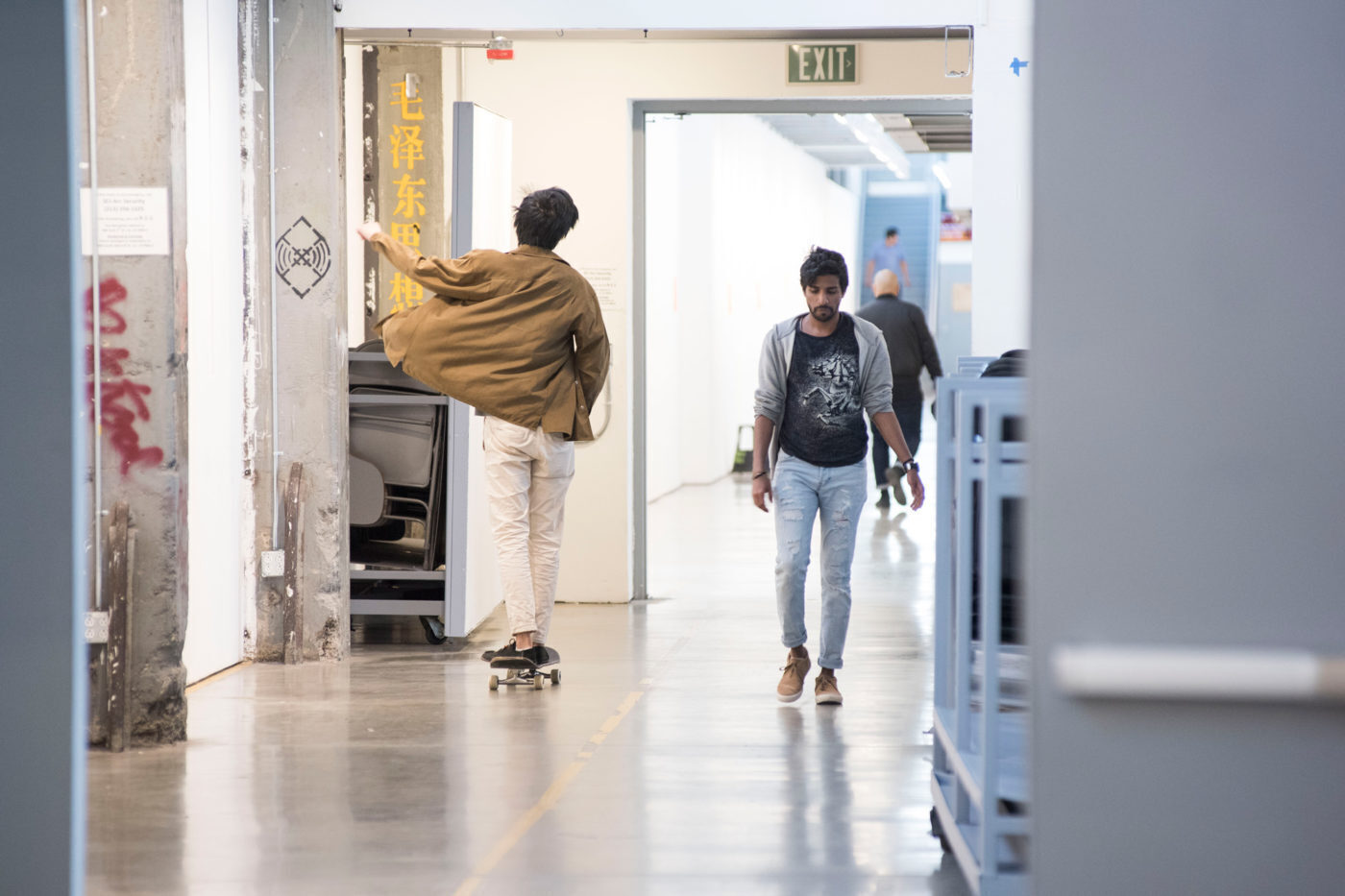 two male students walking and skating through hall of architecture school SCI-Arc