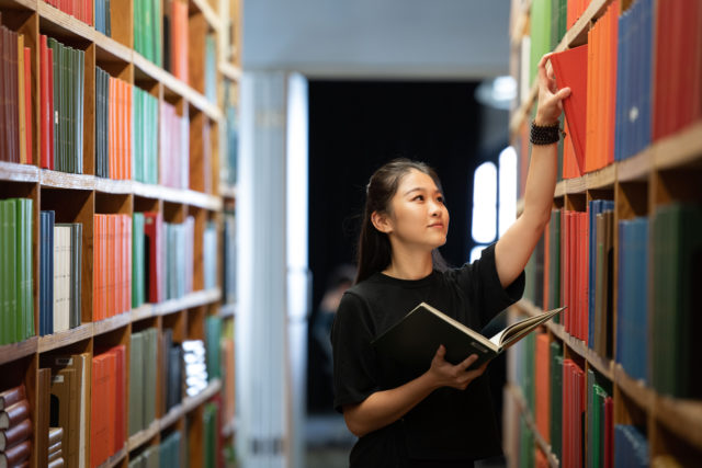 student wearing black in library of books