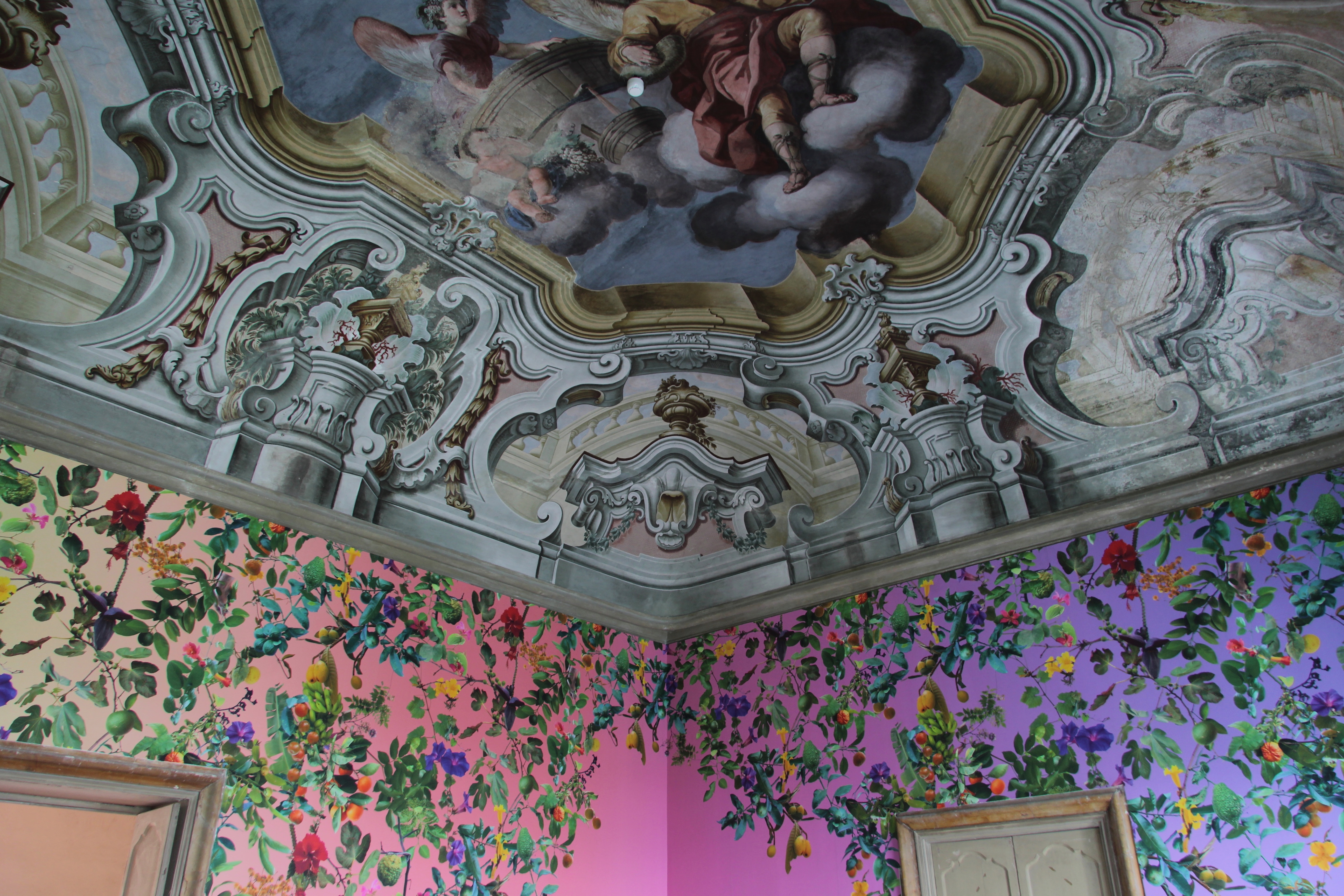 A pink room with plant wallpapers and an art deco ceiling