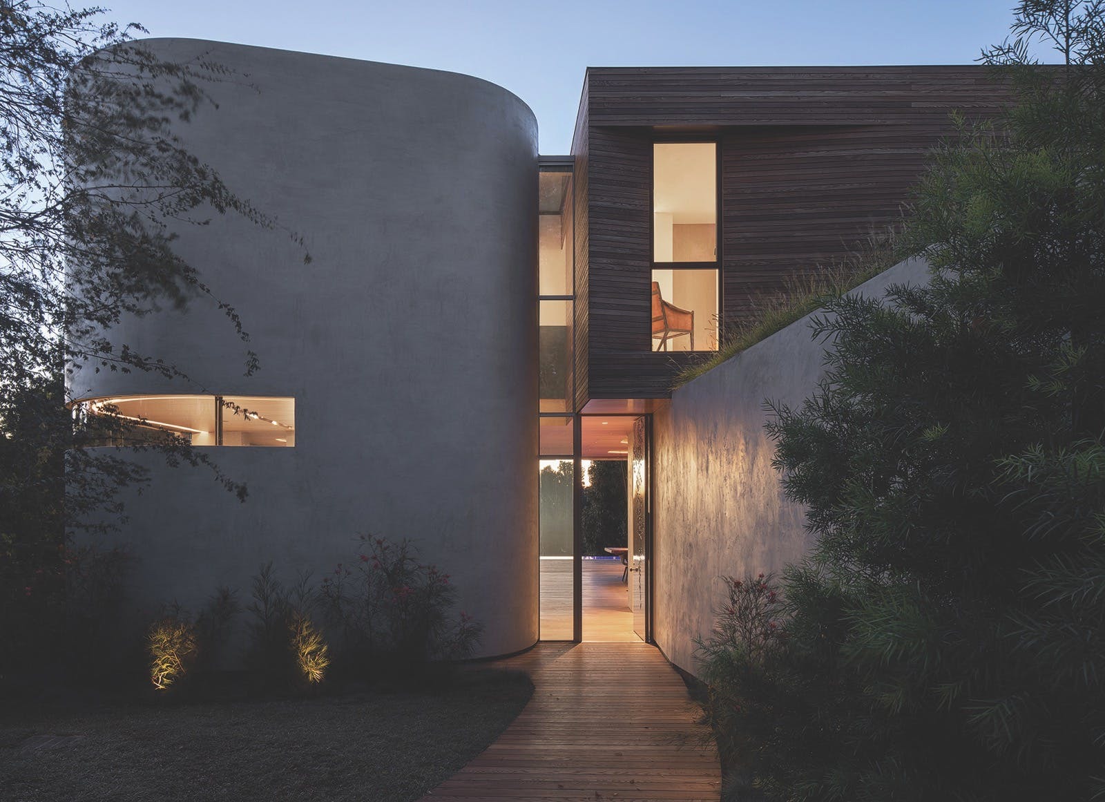 Building with a curved concrete wall next to a wood cladded box