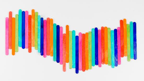 Bunt bemalte Holzstäbchen, aneinandergereiht, die eine Brücke darstellen