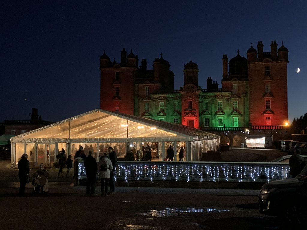 Marquee in front of Drumlanrig Castle lit up in red and green - a Christmas market is one of the Christmas events across the South of Scotland this year.