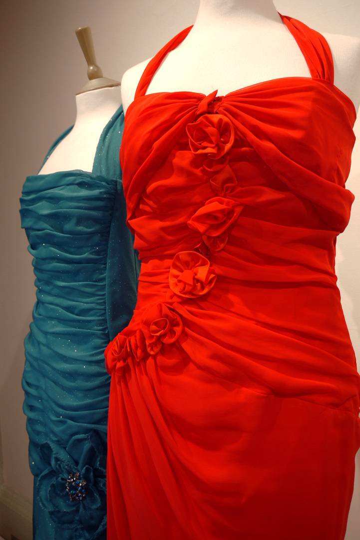 Two elegant evening dresses - one turquoise blue with ruched detail and the other scarlet with applied floral decoration, Mary Beck