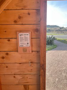 Photograph of a Scottish Islands Passport stamping point showing an information board and a brass rubbing plate mounted on a wooden back