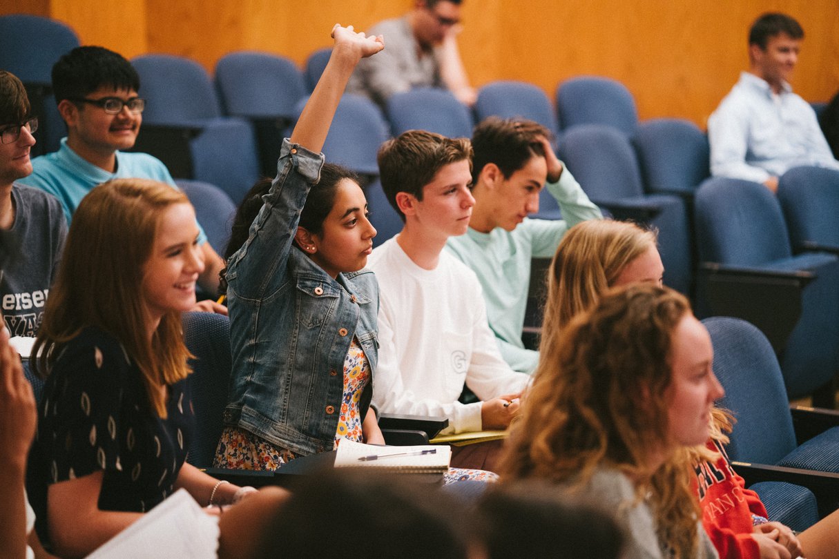 Students raising hands in lecture hall.