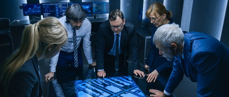 High angle shot of team talking while standing around digital touch screen table