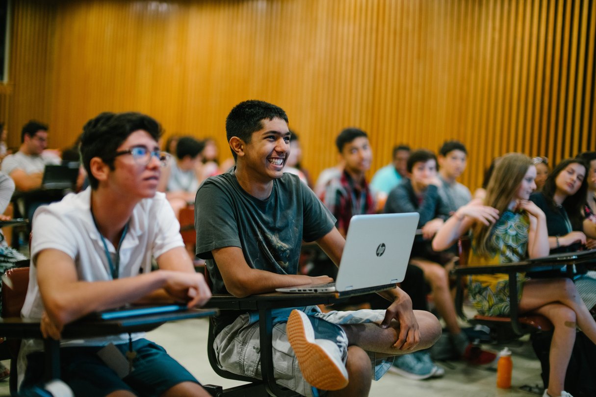 Students sitting in desks listening in lecture hall.