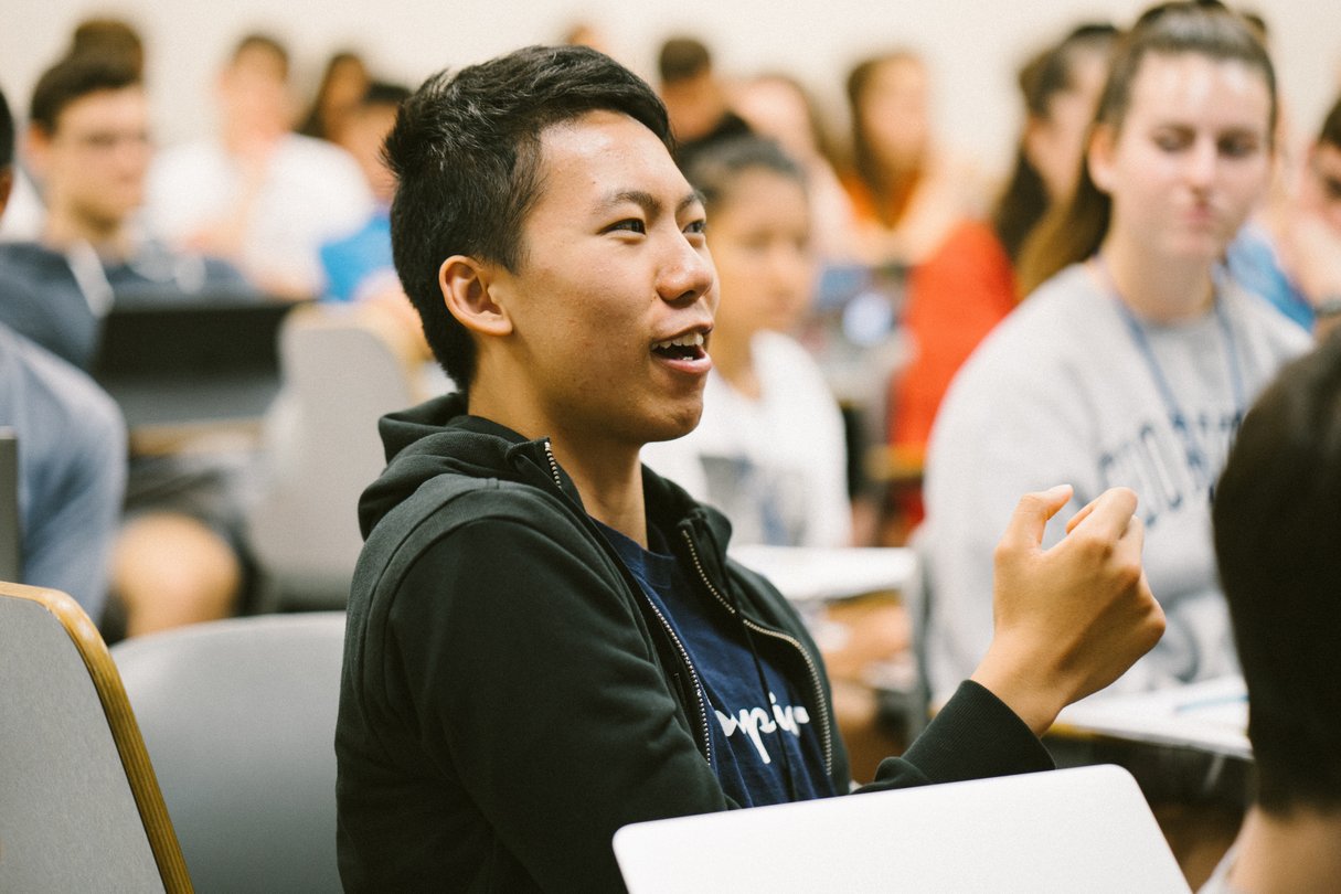 Student sitting up in seat in lecture hall to answer a question.