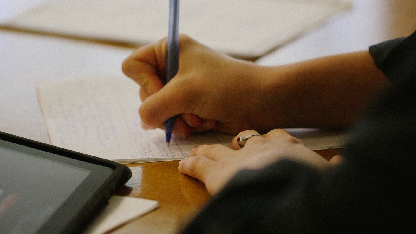 Close up image of a hand writing with a pen.