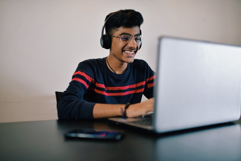 Male student smiling at computer at desk.