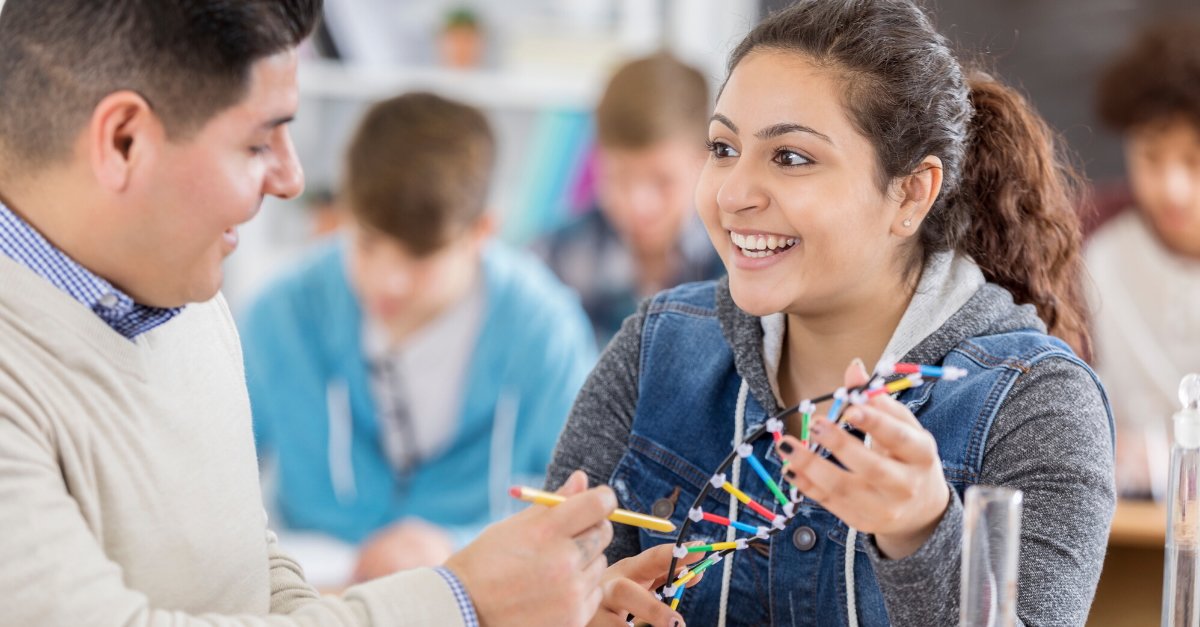 Female student smiling with plastic structure of DNA in her hands.