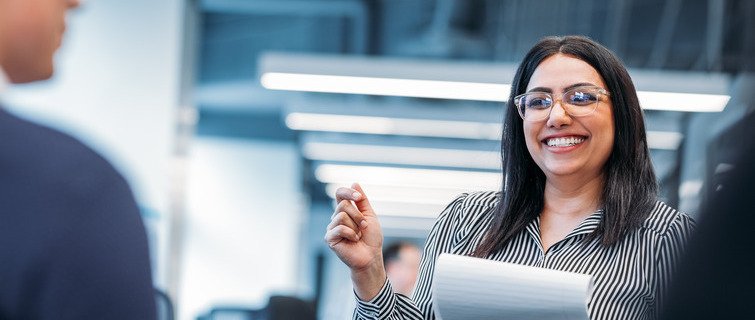 Smiling woman speaking with colleagues in office meeting.