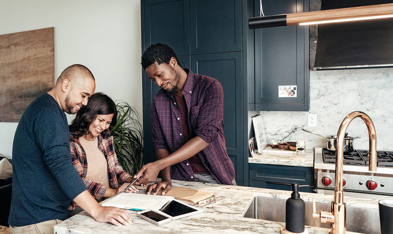 A contractor going over plans with a couple in a kitchen.