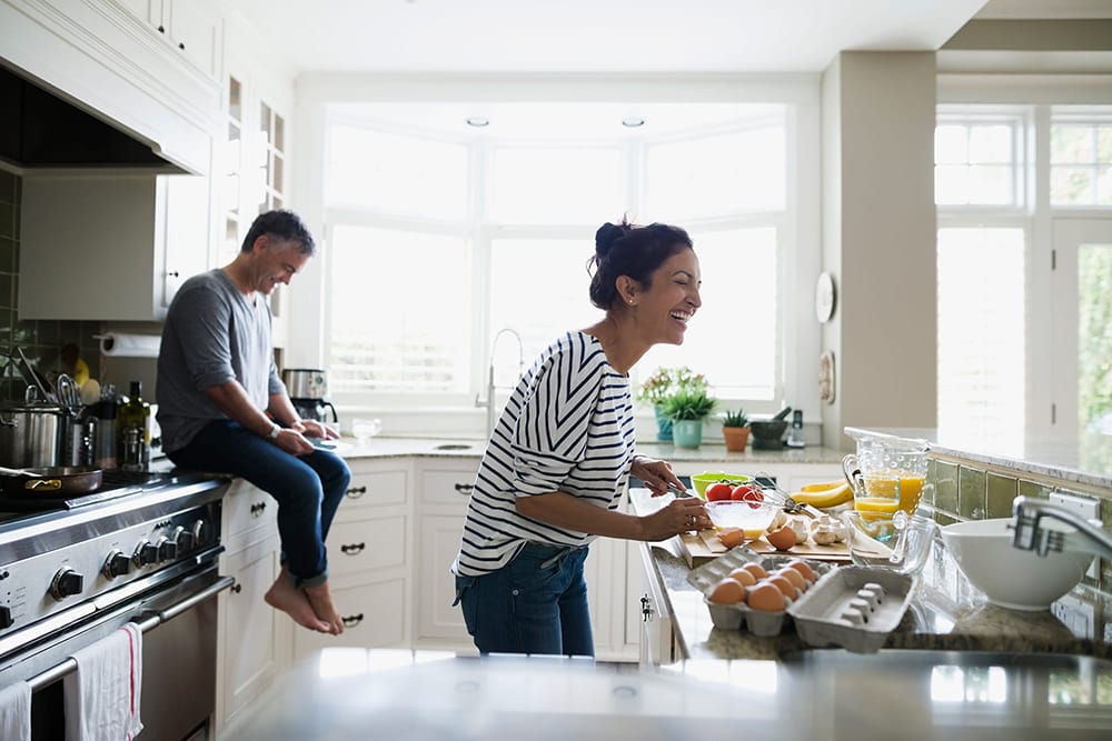 couple in their brightly lit kitchen cooking a meal together