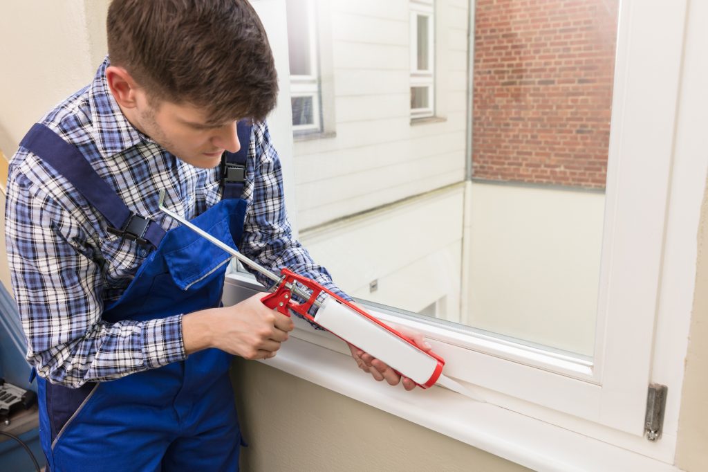 man is air sealing using caulk around windows