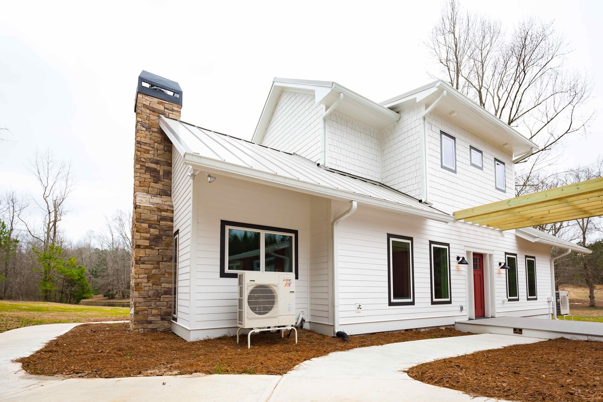 outdoor heat pump condenser unit on exterior of white new construction home