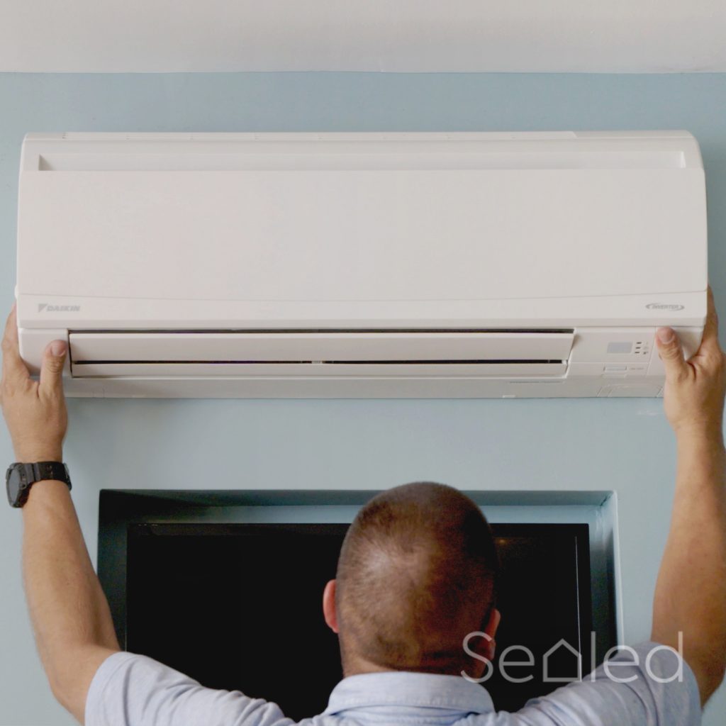 man installing indoor mini split heat pump unit