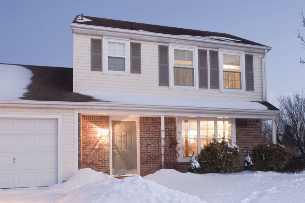 exterior of modest two-story home in snow and ice dams on roof