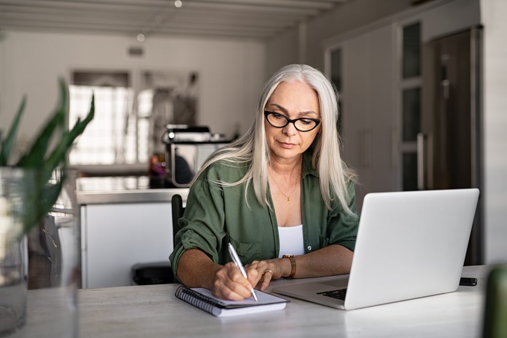 mature fashionable woman working on weatherization assistance application at kitchen table