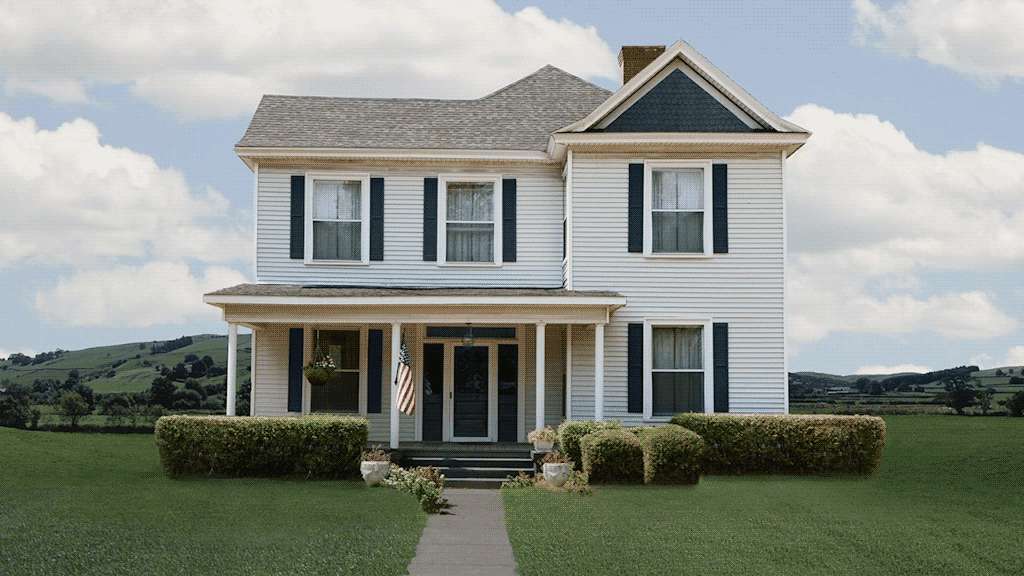 white two-story house on perfect day with clouds in blue sky and hills in background