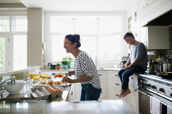 man and woman cooking and laughing in a brightly lit kitchen with efficient appliances