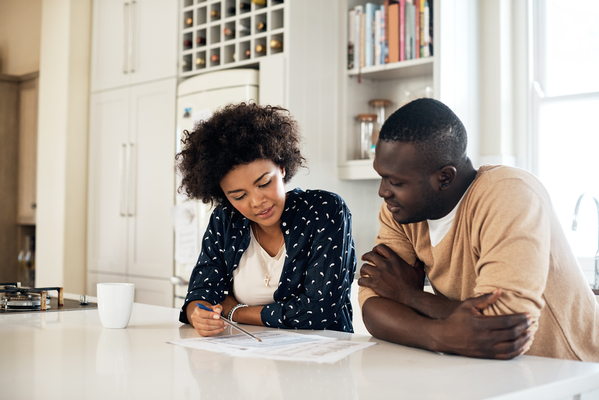 young couple sits in well-lit bright kitchen overlooking their energy audit results