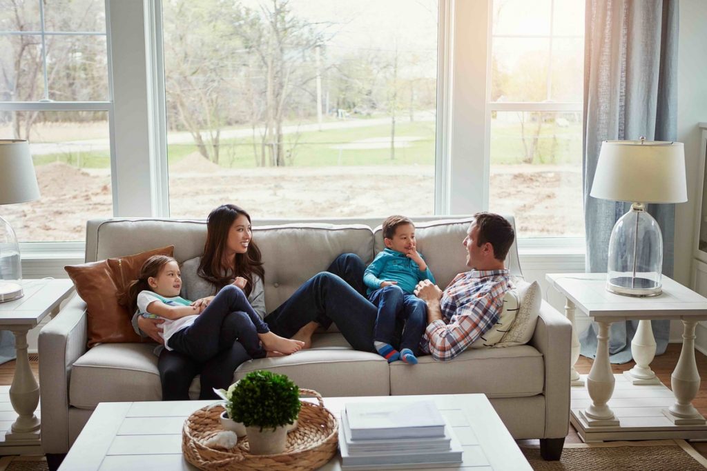 Joyful family spending time together on comfortable couch in front of window