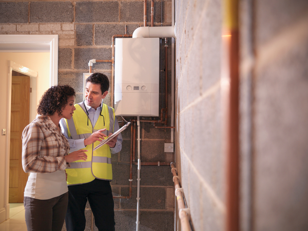 An energy auditor assists a homeowner in understanding her home energy upgrade options in the garage near a boiler