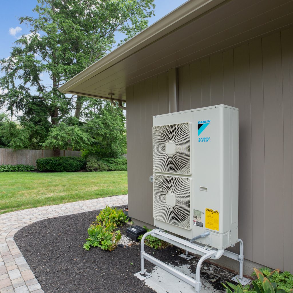 Daikin heat pump condenser outside unit against exterior of house