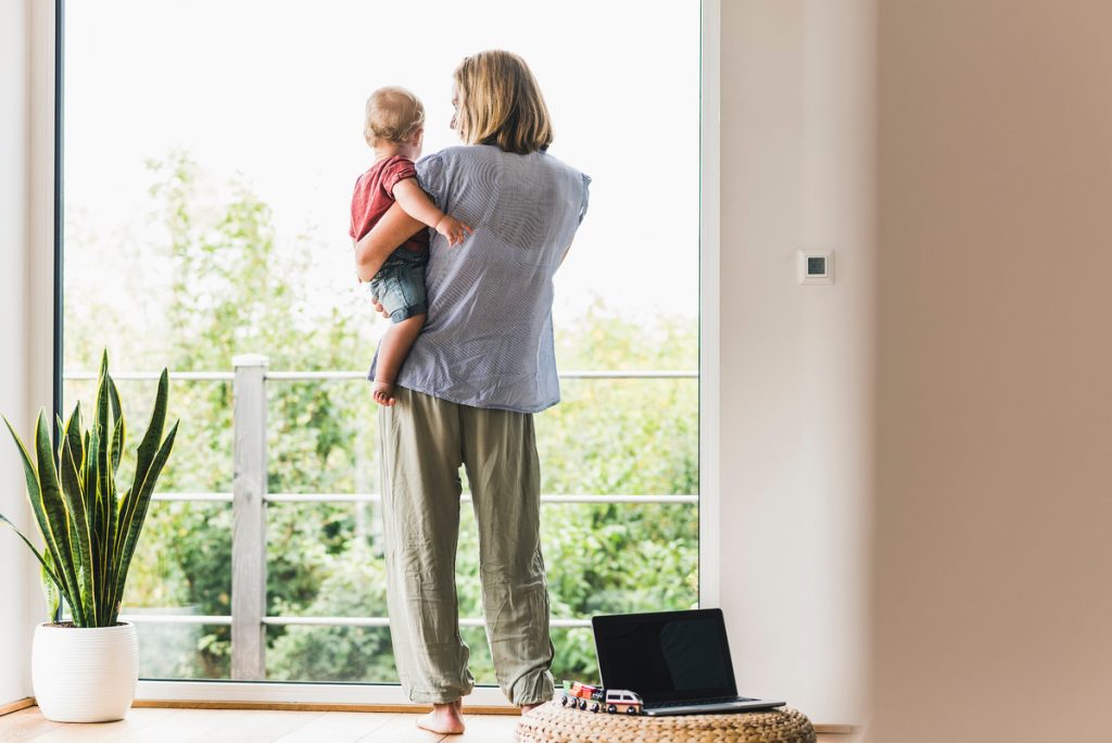 Mother holding son looking out a window.