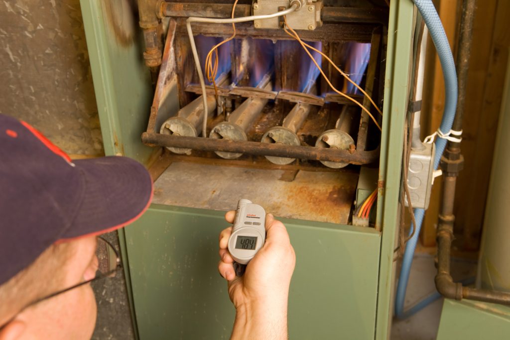 A homeowner looks at the inside of his furnace