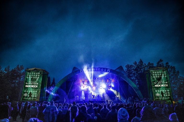 Rockfestivaalin päälava ja yleisömeri illan hämärässä.