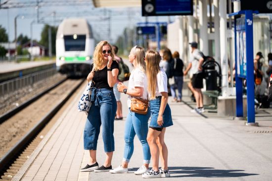 Three young people are standing at the train station.